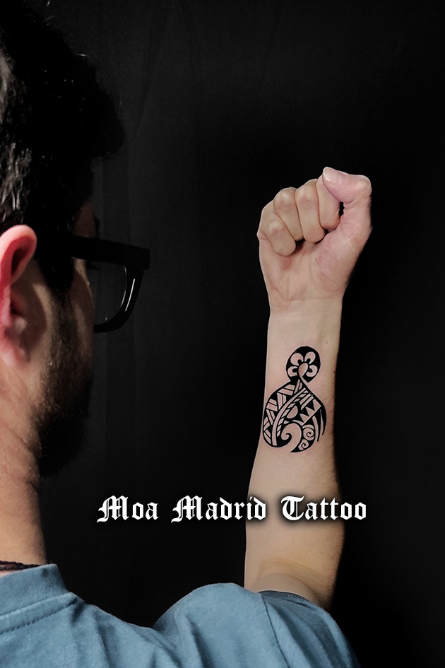 Tatuaje en el antebrazo de anzuelo maorí (prosperidad) y nudo maorí (unión de personas)