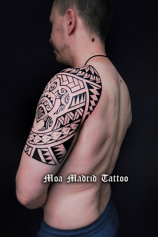 Vista trasera del tatuaje polinesio en hombro y parte superior del brazo
